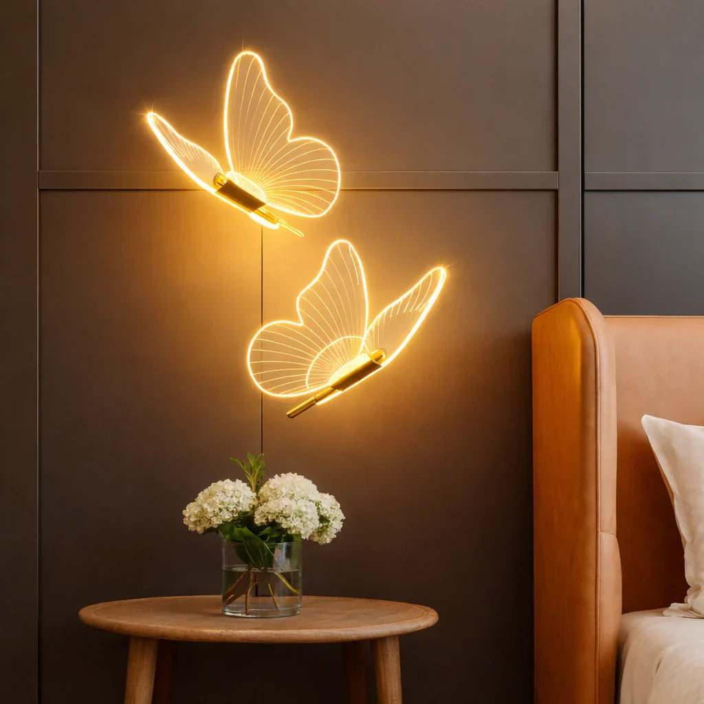 imagem focando em dois pendentes de luminária em formato de borboletas que estão penduradas ao lado de uma cabeceira de cama, abaixo mostra uma mesinha de centro que tem um pequeno vaso com flores brancas dentro